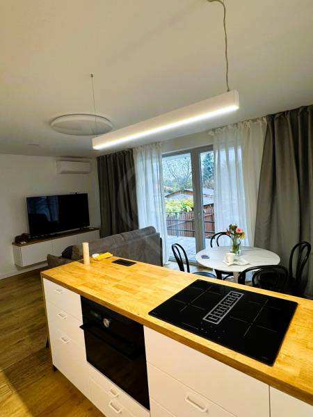 Konyhasziget főzőlappal, étkezőasztal és kanapé egy családi házban.