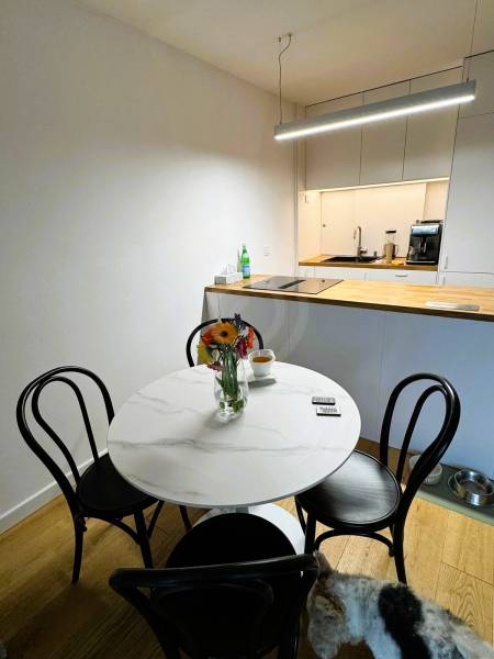 Ebédlő egy családi házban kerek asztallal, virágokkal és fa mintázatú padlóval.