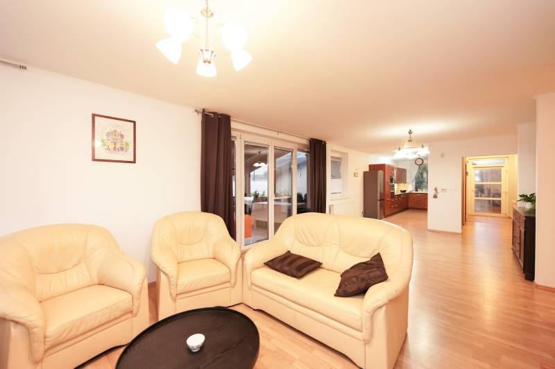 Családi ház nappalija krémszínű kanapéval és fa mintázatú padlóval.