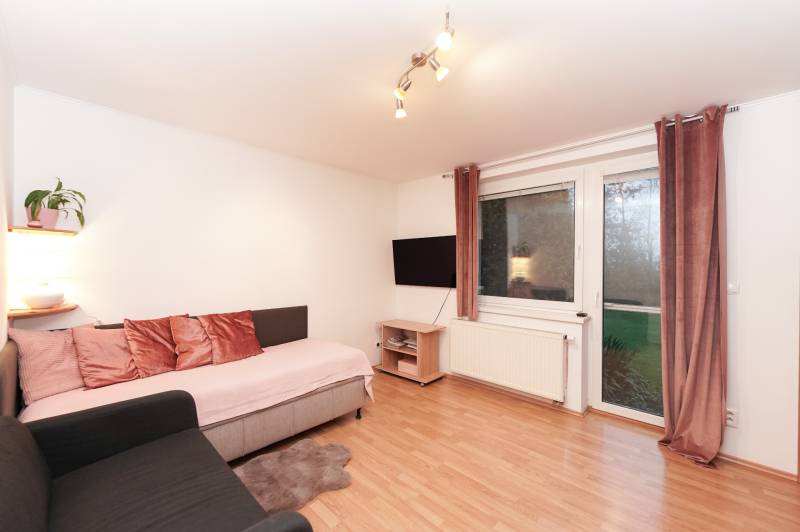 Nappali egy családi házban kanapéval, televízióval és fa dekorációjú padlóval.