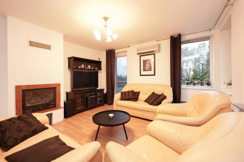 Nappali egy családi házban kandallóval, bőr kanapékkal és fa dekorációjú padlóval.