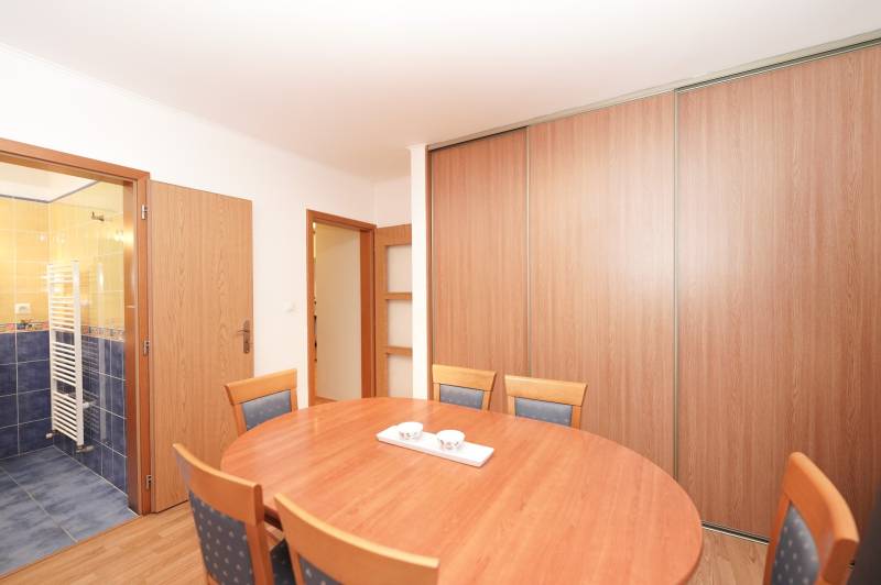 Étkező sarok egy családi házban fa kiegészítőkkel és háttérben fürdőszobával.