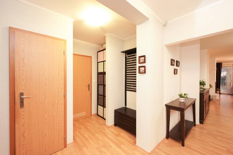 Családi ház belső tere fa dekorációjú padlóval, színes szekrényekkel és virágcseréppel.