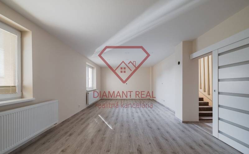 Tágas szoba fa mintás padlóval és lépcsővel egy családi házban.