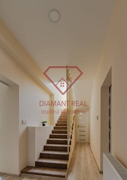 Családi ház belső tere szőnyeggel borított lépcsővel és fa dekorációjú padlóval.