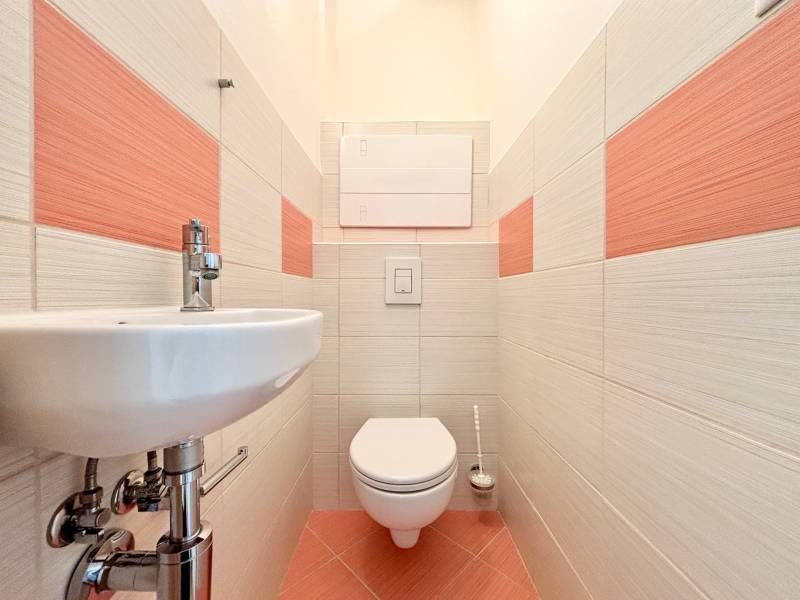 Kétszobás lakás fürdőszobája mosdóval és pasztell csempékkel.