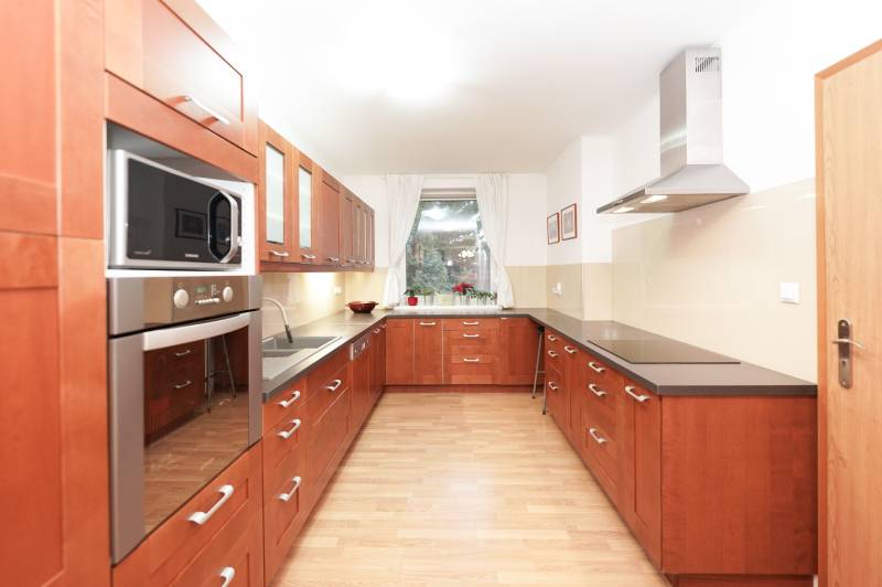 Családi ház konyhája fa dekorációval, főzőlappal és mikrohullámú sütővel.