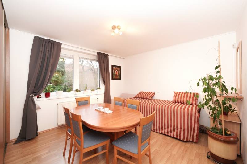 Családi ház étkezője kör alakú asztallal, székekkel, kanapéval és fa dekoros padlóval.