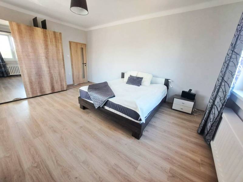 Hálószoba családi házban ággyal, ruhásszekrénnyel és fa dekorációjú padlóval.