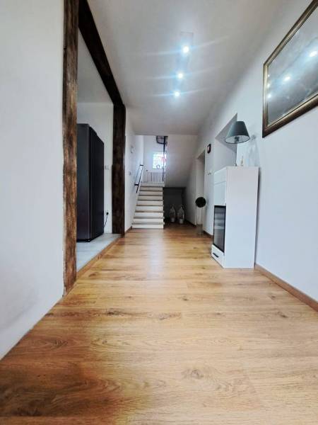 Családi ház belső tere fa dekorációjú padlóval és háttérben lépcsővel.