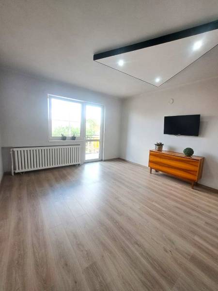 Nappali családi házban fa dekorációjú padlóval, televízióval és komóddal.