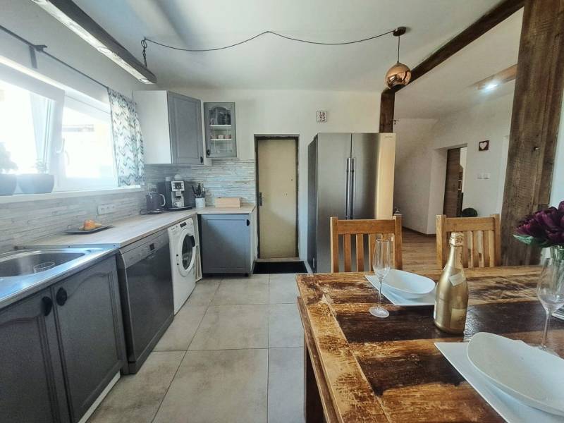 Konyha egy családi házban, fa asztallal és modern készülékekkel.