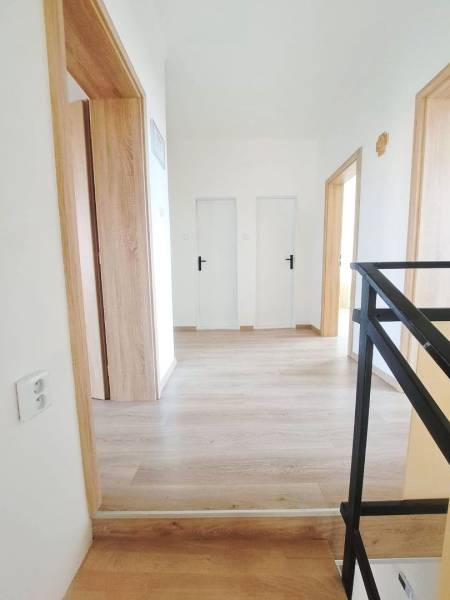 Családi ház belső tere fa dekorációjú padlóval és fehér ajtókkal.