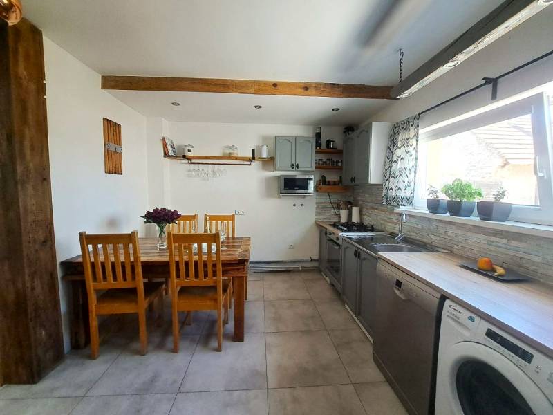 Konyha egy családi házban fa mennyezeti gerendával és sorozat fa székekkel.