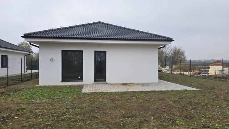 Családi ház Cíferen fehér homlokzattal és terasszal a kertben.