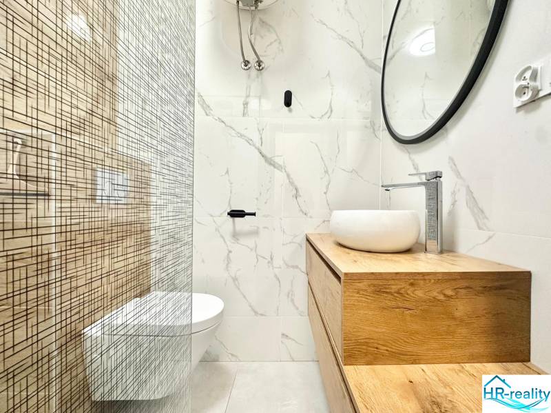 Fürdőszoba egy nyaraló apartmanban minimalista dizájnnal és hangsúlyos fa dekorációval.