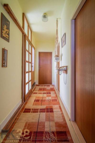 Folyosó egy családi házban szőnyegpadlóval, faajtókkal és faldekorációkkal.