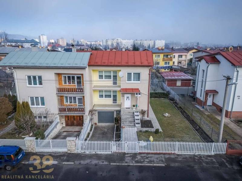 Családi ház Poprádon dupla tetővel, fehér kerítéssel és rendezett kerttel.