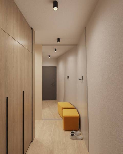 Egy épület belső tere fa dekor padlóval, ruhásszekrény, tükör és sárga ülőhely.