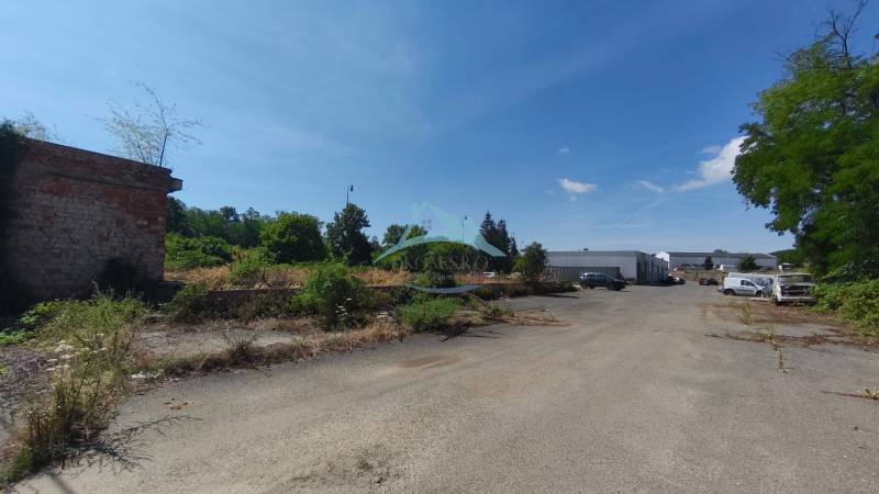 Kereskedelmi telkek a Lučenecká úton Nagykürtösön régi épületekkel és növényekkel.