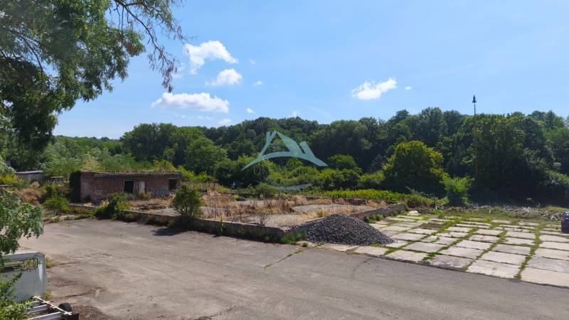 Kereskedelmi telkek a Nagykürtösi Losonci úton elhagyott épülettel, fákkal körülvéve.