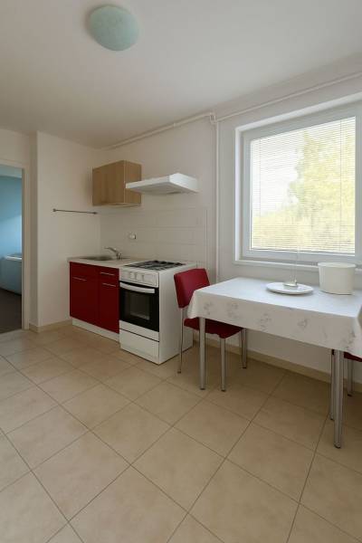 Konyha piros szekrénnyel, asztallal és két székkel egy családi házban.