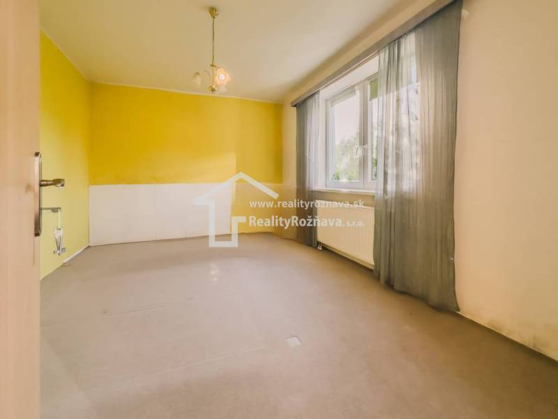 Szoba egy családi házban nagy ablakkal, sárga falakkal és függönyökkel.