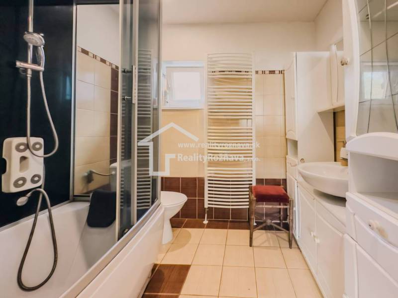 Fürdőszoba családi házban káddal, zuhanyzóval, mosdóval és radiátorral.