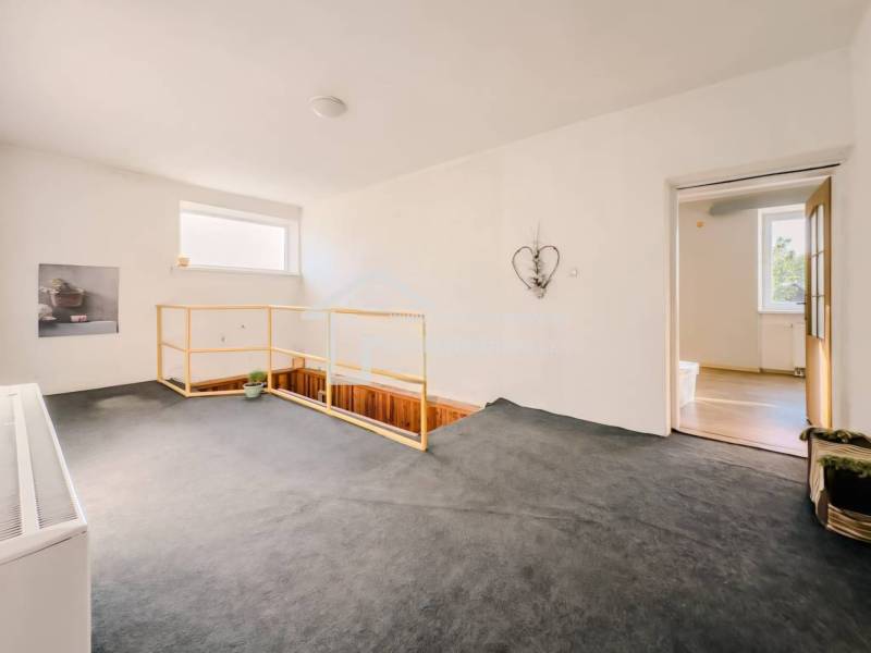 Családi ház belső tere szőnyeggel, lépcsővel és egyszerű fali dekorációval.