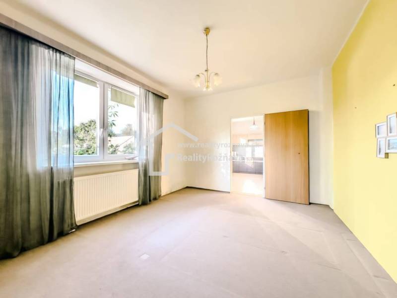 Szoba nagy ablakkal, radiátorral és átjáróval egy családi házban.