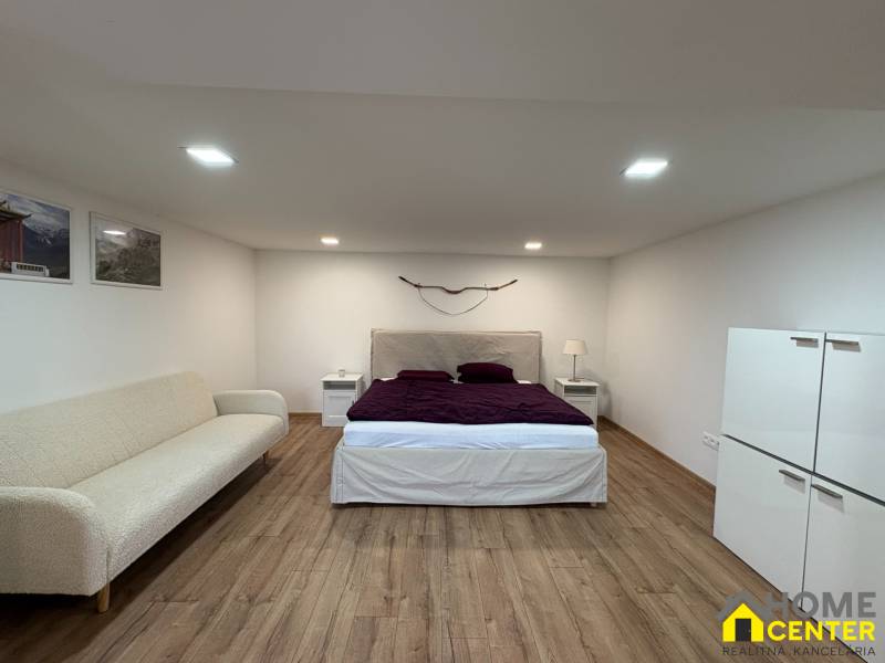 1 szobás lakás belső tere ággyal, kanapéval és fa dekorációjú padlóval.