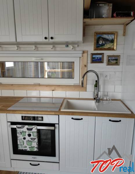 Konyhapult családi házban fehér szekrényekkel, mosogatóval és beépített sütővel.