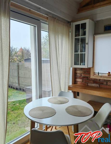 Étkező sarok egy családi házban, fa dekoros padlóval, téglafallal és nagy ablakokkal.