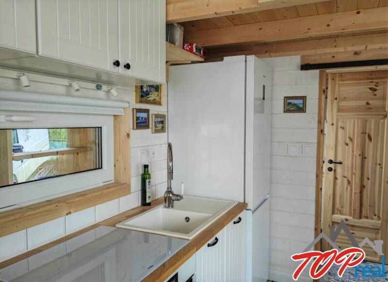 Konyha a családi házban fehér bútorokkal és fa elemekkel.