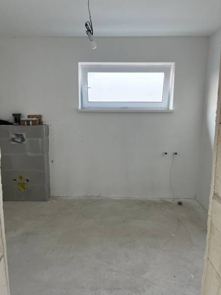 Egy családi ház üres szobája fa dekorációval és keskeny ablakkal a falon.