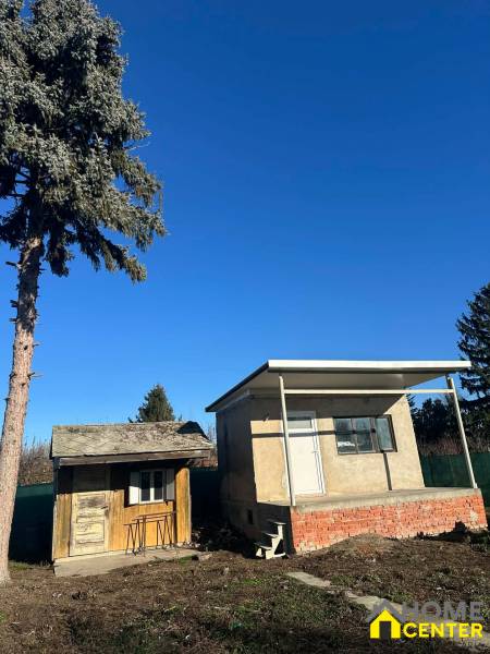 Kertek az Újtelepen Komáromban kis épületekkel és tűlevelű fával.