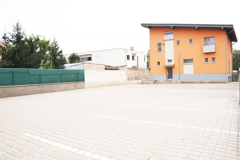 Narancssárga épület Sálo-ban meredek tetővel és szilárd burkolatú parkolóval.