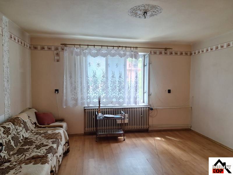 Nappali egy családi házban fa mintázatú padlóval és kanapéval.