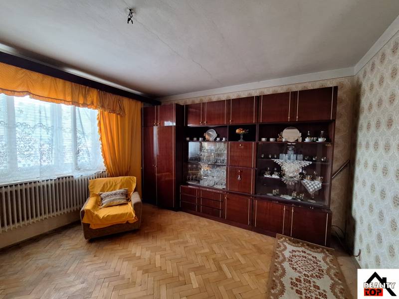 Nappali családi házban, karosszékkel, bútorokkal és fa dekorációjú padlóval.