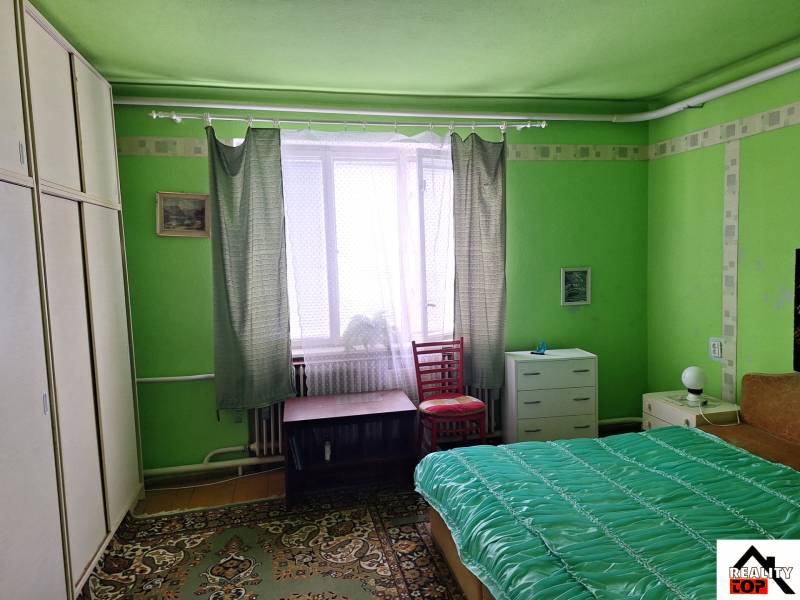 Zöld szoba családi házban ággyal, szekrénnyel és szőnyeggel.