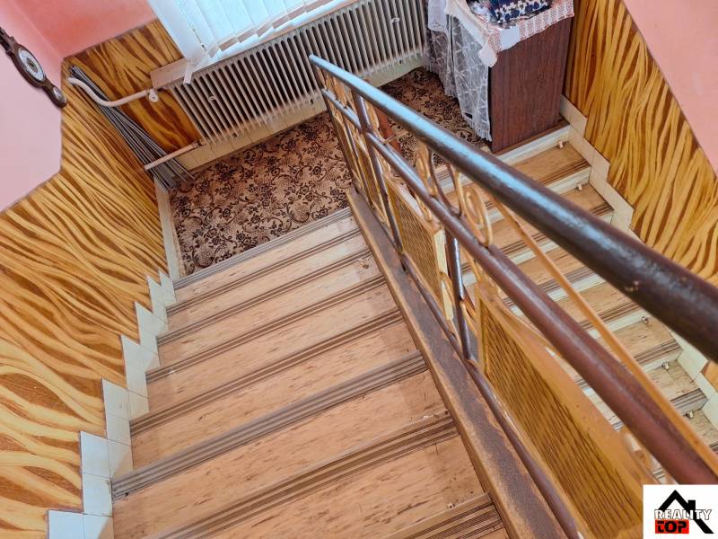 Lépcső szőnyeggel és fa dekor padlóval családi házban.