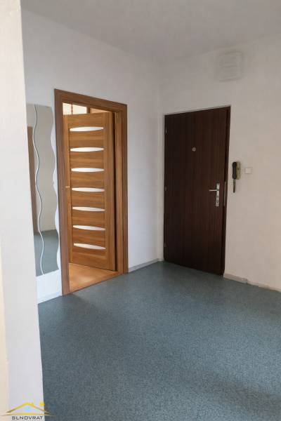 Előszoba egy háromszobás lakásban fa dekoros ajtókkal és tükörrel.