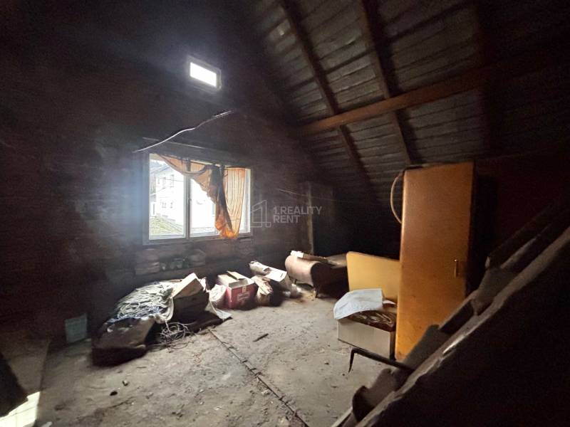 Tetőtéri szoba ablakokkal egy családi házban, tele régi tárgyakkal és bútorokkal.