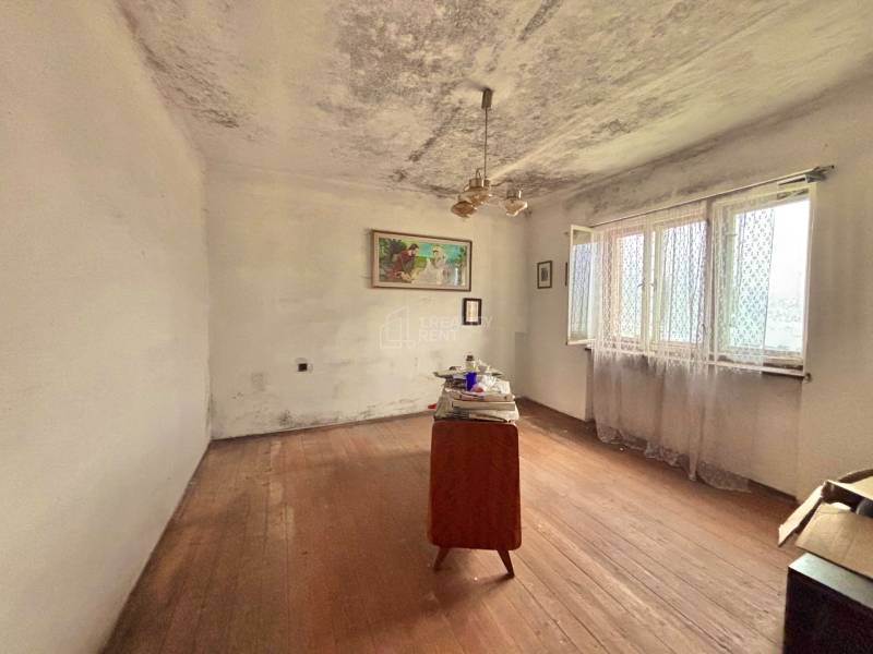 Szoba egy családi házban egyszerű bútorokkal és fa dekoros padlóval.