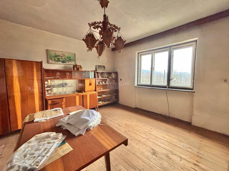 Szoba családi házban fa dekorációval, vintage bútorokkal, csillárral és nagy ablakkal.