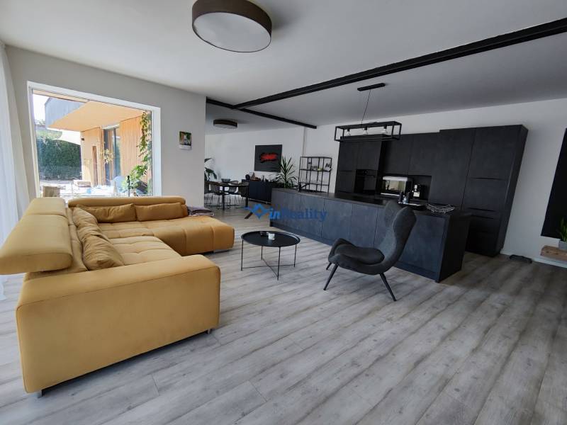 Nappali egy családi házban, fa mintázatú padlóval és kényelmes kanapéval.