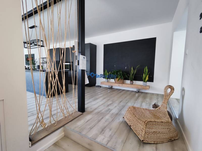 Családi ház belső tere fa dekorációjú padlóval, növényekkel és kötél dekorációval.