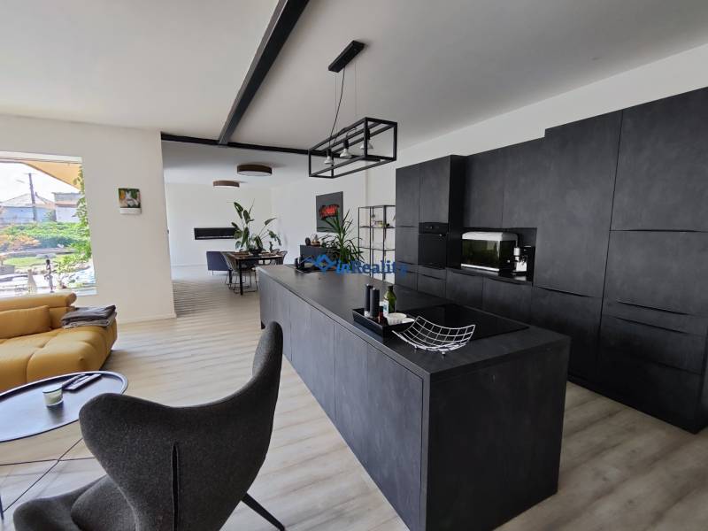 Nappali összekötve a konyhával egy családi házban, fa mintázatú padlóval.