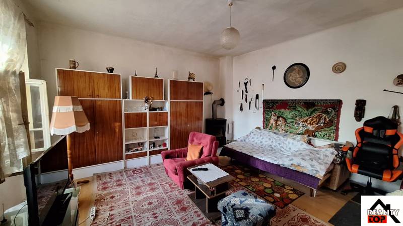 Nappali egy családi házban szőnyeggel, kanapéval és polcos tárolórendszerrel.