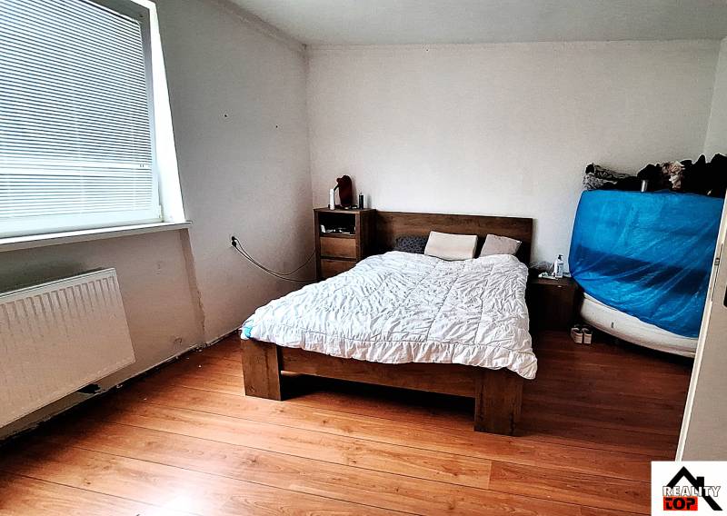 Hálószoba családi házban ággyal, komóddal és fa dekorációs padlóval.